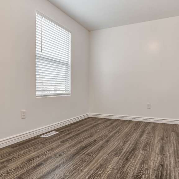 an empty room with wood floors and white walls and a window