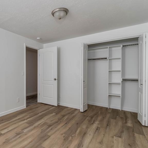 an empty room with white walls and wooden floors and white closets