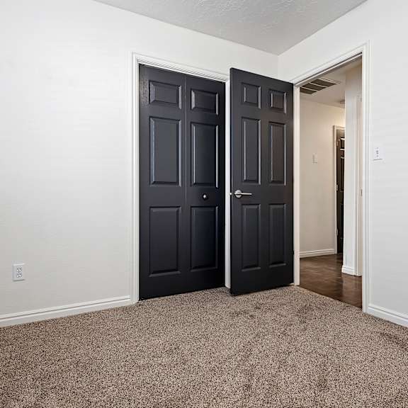 an empty room with two doors and a carpeted floor