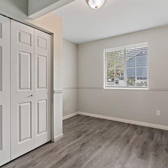 an empty bedroom with white doors and a window