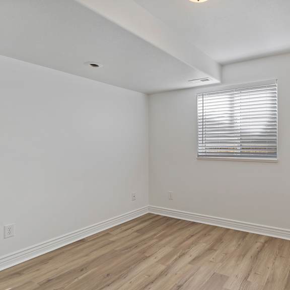 a room with wooden flooring and a window with blinds.