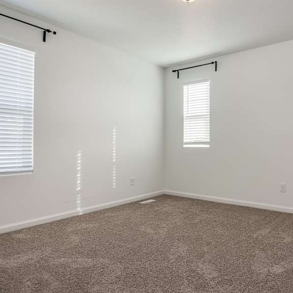 a room with a carpeted floor and a window with blinds.