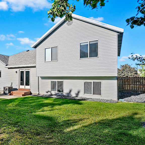 a backyard with a white house and a green lawn