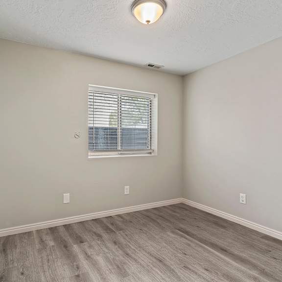 an empty bedroom with wood floors and a window