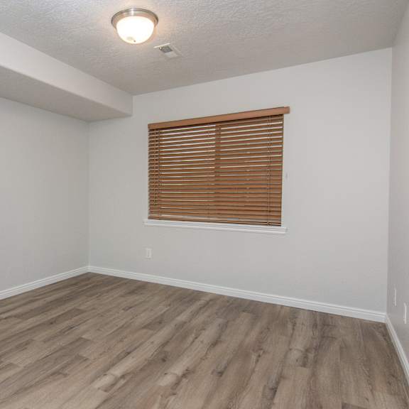 an empty living room with wood flooring and a window