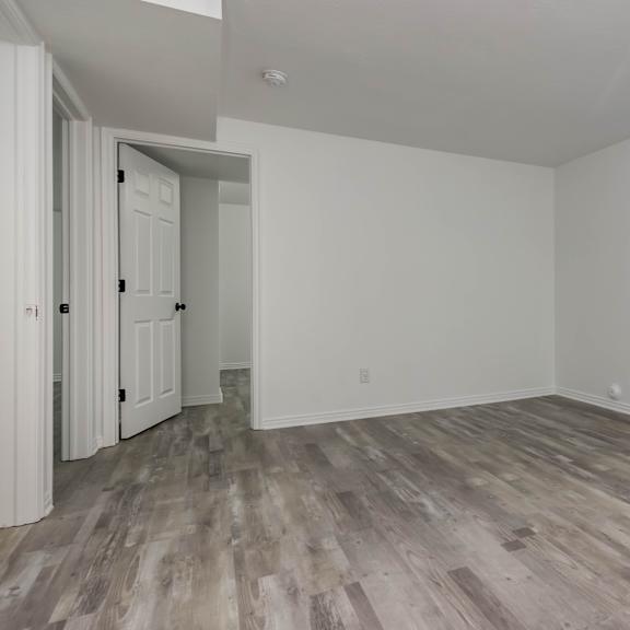 a room with white walls and wood flooring with a window.
