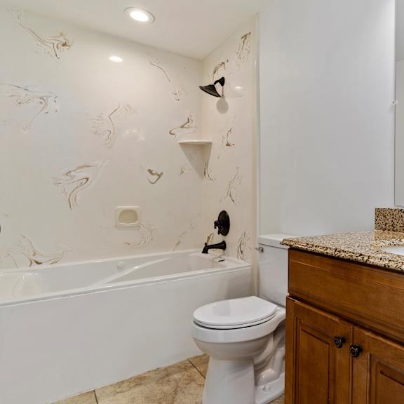 a white toilet sits in a bathroom with a marble counter top.