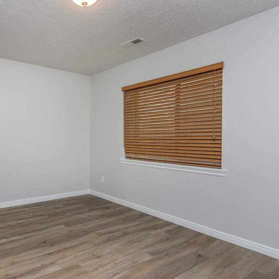 an empty bedroom with wooden floors and a window