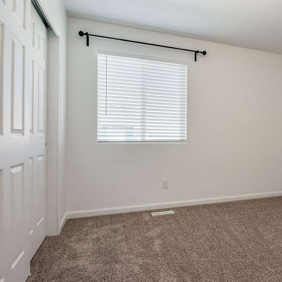 a room with a carpeted floor and a window with blinds.