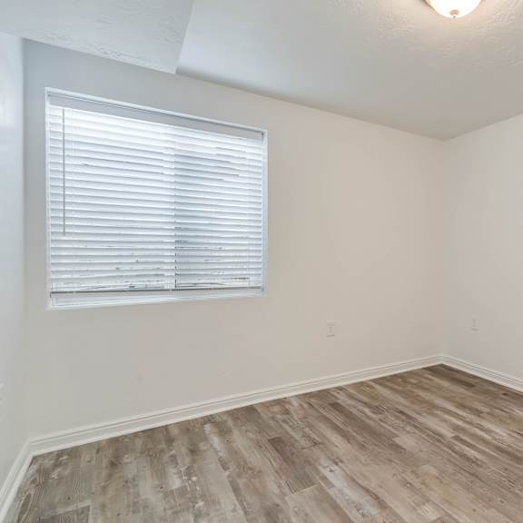 the living room of an apartment with wood flooring and a window