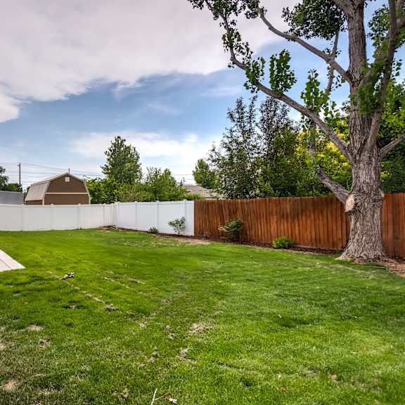 the backyard of a house with a fence and a grassy yard