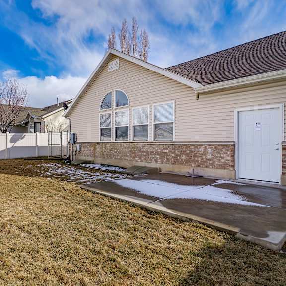 the front of a house with a yard and a white fence