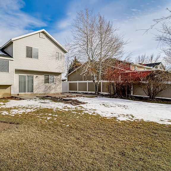 a house with a brown fence and a snow-covered ground.