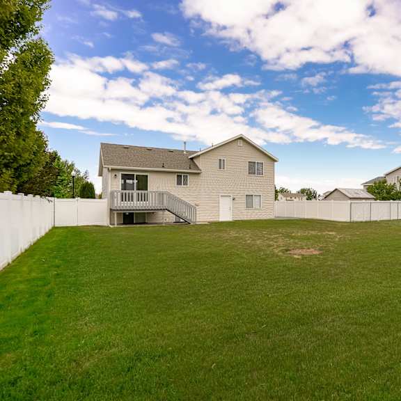 a backyard with a large grassy area and a few houses in the background.