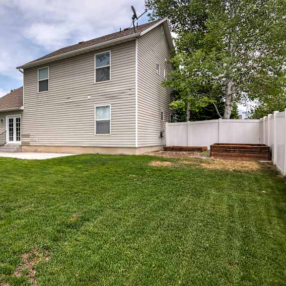 the back of a house with a yard and a white fence