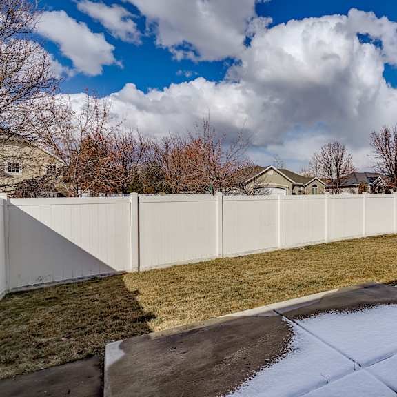 the back yard of a house with a white fence and snow on the ground