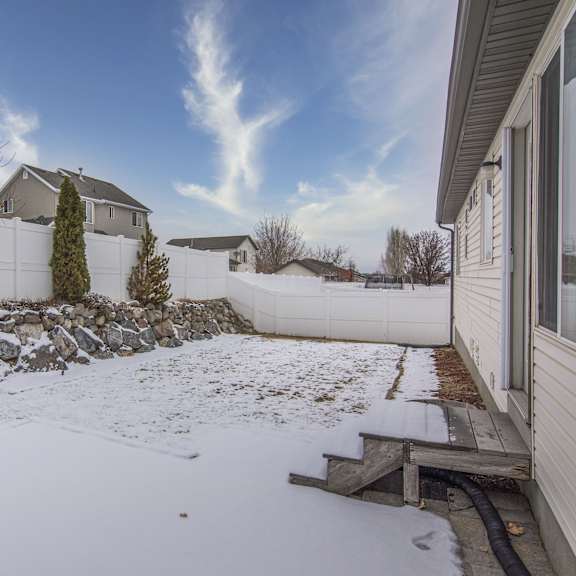 a backyard covered in snow with a fence and a house