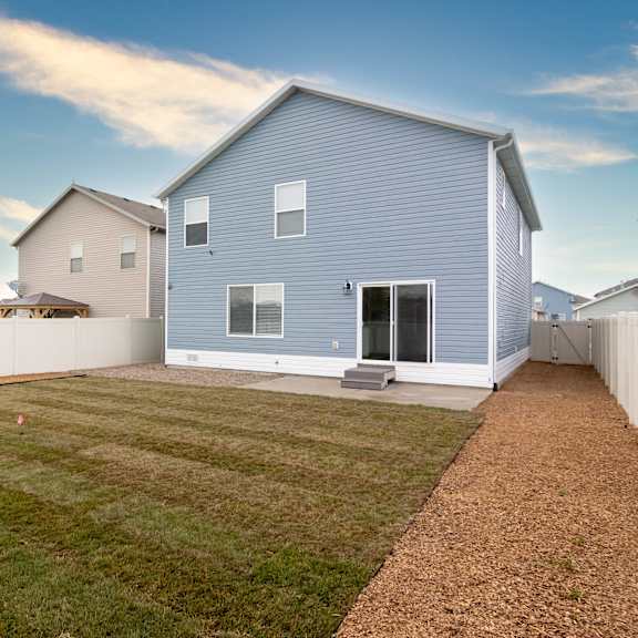 a blue house with a white fence and a green lawn.