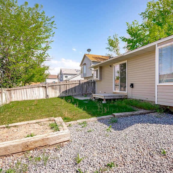 a mobile home with a gravel driveway and a wooden fence.