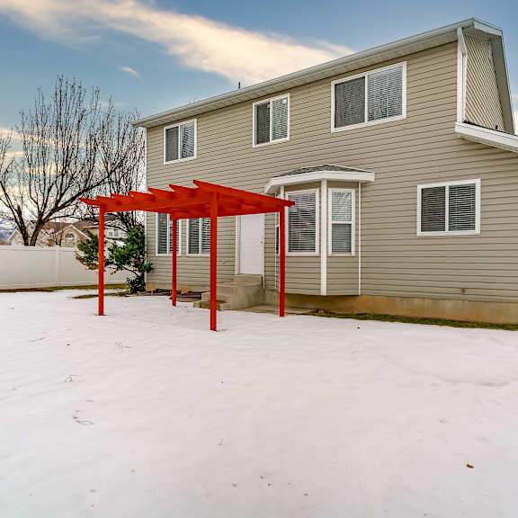 a house with a red pergola in the snow.