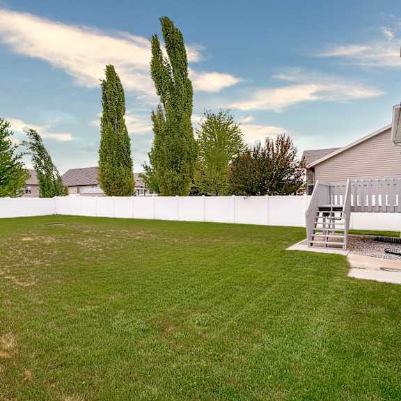 a backyard with a white fence and a tree.