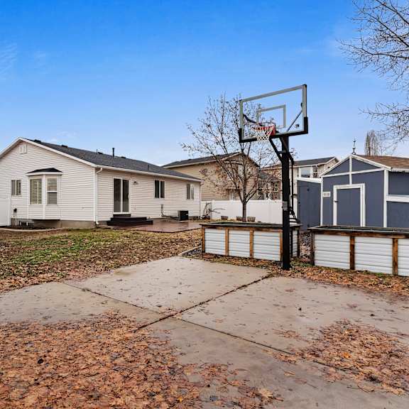 a basketball hoop stands in the middle of a driveway with a house in the background.