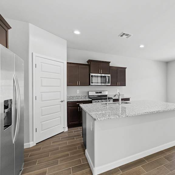 a kitchen with a white island and brown cabinets.
