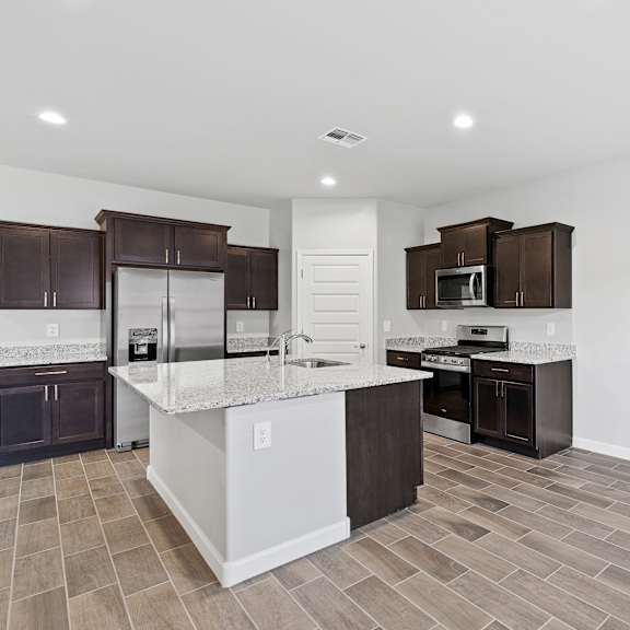 a kitchen with a white island and dark brown cabinets.