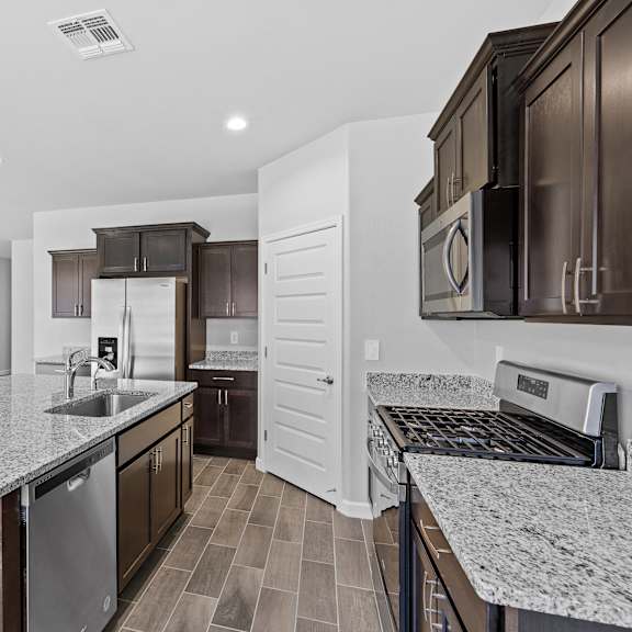 a modern kitchen with dark wood cabinets and granite countertops.