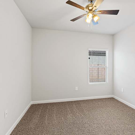 a room with a ceiling fan and carpeted floor.
