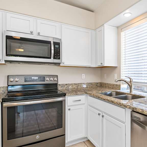 a kitchen with a stove, microwave, dishwasher, and sink.