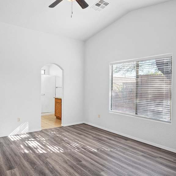 an empty living room with a large window and wood flooring