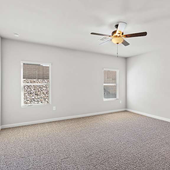 a room with a ceiling fan and two windows.