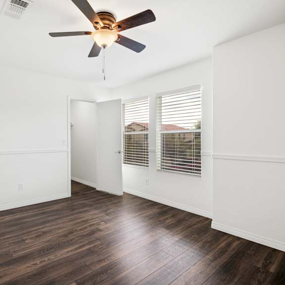 a room with a ceiling fan and wooden flooring.