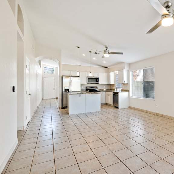 a spacious kitchen and living room with a tile floor and ceiling fan.
