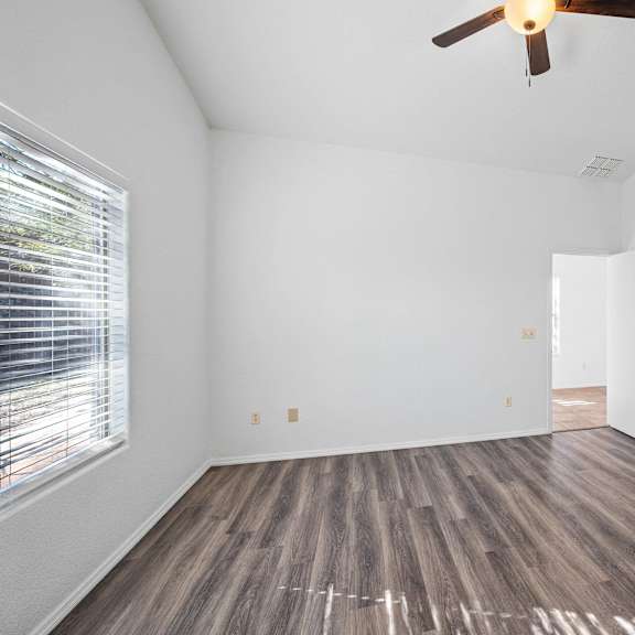 an empty room with a ceiling fan and a window