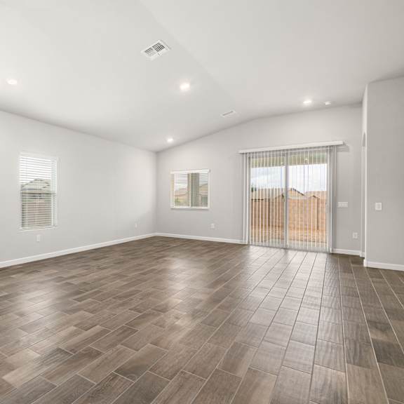 a large empty room with wooden flooring and a chandelier.