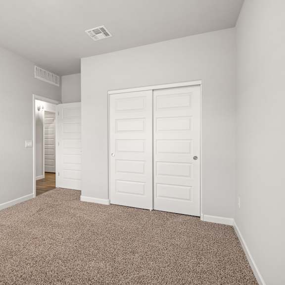 a room with a carpeted floor and two white doors.
