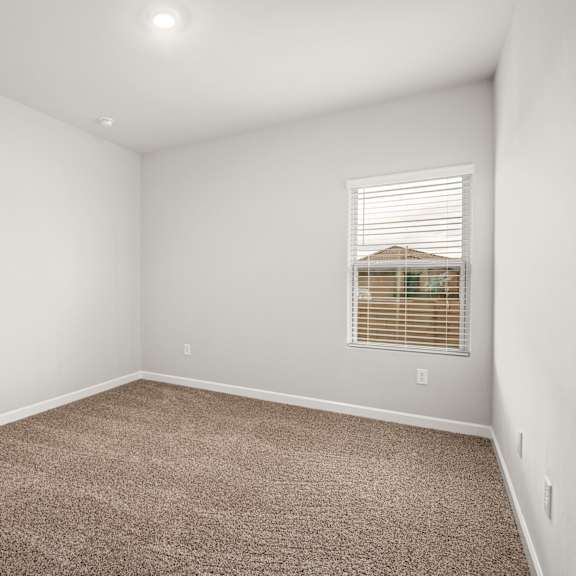 a room with a carpeted floor and a window with blinds.