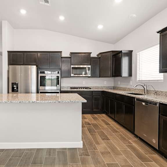 a modern kitchen with a white island and dark brown cabinets.