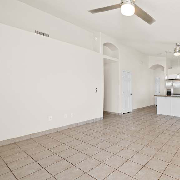 a spacious kitchen with a fan and a tiled floor.