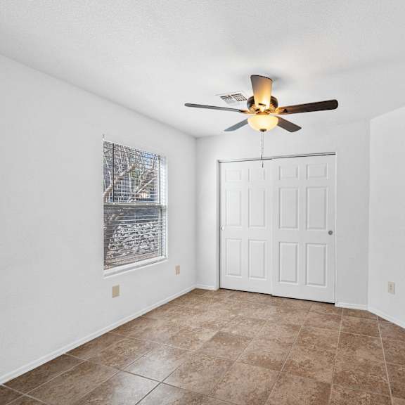 an empty room with a ceiling fan and a window