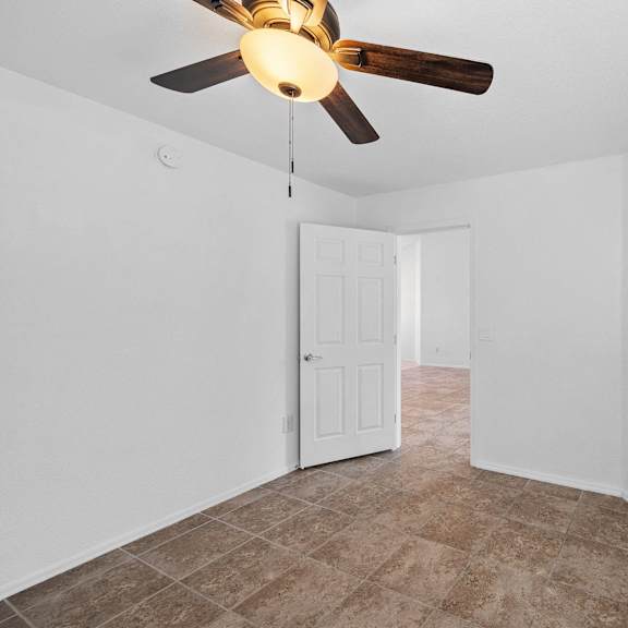 an empty room with a ceiling fan and white walls