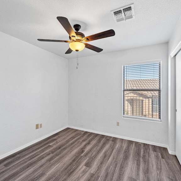 an empty room with a ceiling fan and a window