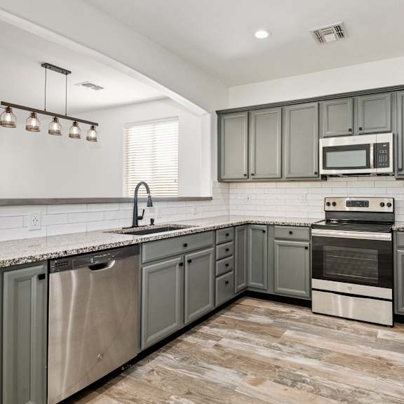 a kitchen with stainless steel appliances and grey cabinets.