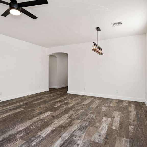 a room with a ceiling fan and wooden flooring.