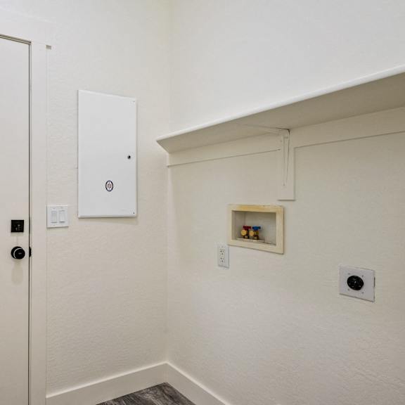 a white door with a black handle and a white wall with a small shelf and a vent.