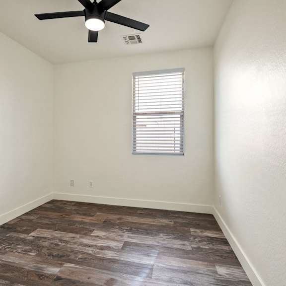 a room with a ceiling fan and a window with blinds.