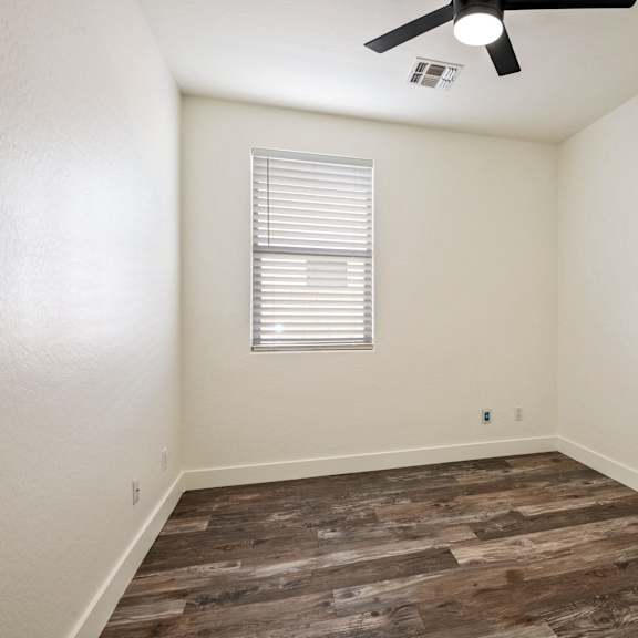 a room with a ceiling fan and a window with blinds.