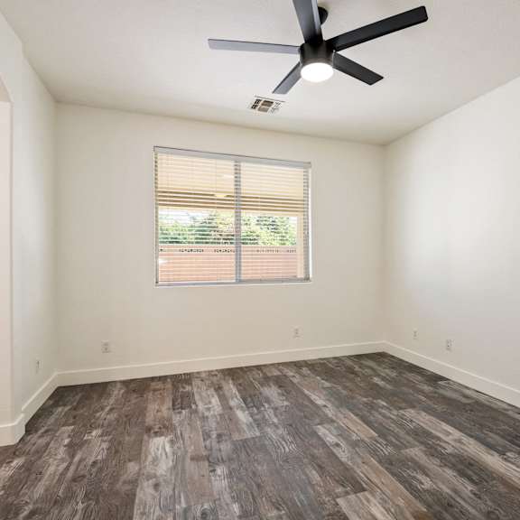 a room with a ceiling fan and wooden flooring.